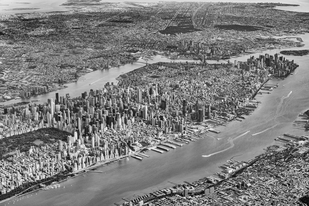 Schwarz-Weiß-Luftaufnahme von Manhattan, dem Hudson River und den dicht bebauten Stadtvierteln von New York aus großer Höhe.