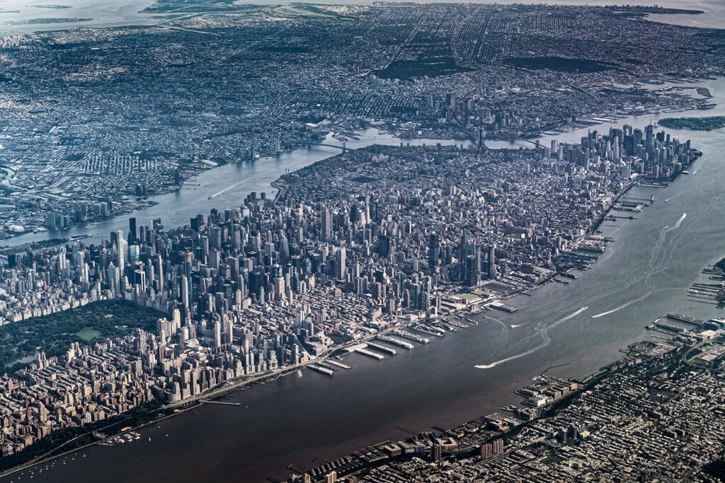New York Departure – Luftaufnahme von Manhattan kurz nach dem Start in Newark. Die Skyline, der Hudson River und die umliegenden Wasserflächen zeigen den Kontrast zwischen dichter Urbanität und der Natur